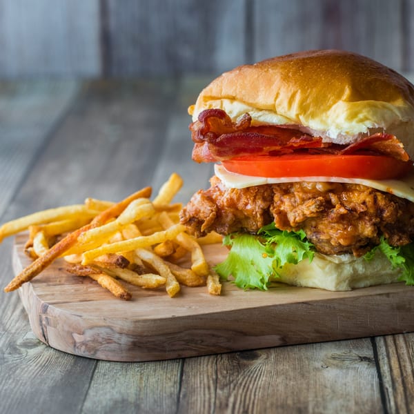 SUPPA'S PIZZA & SUBS fried chicken sandwich with bacon, tomato, cheese, lettuce, and fries.