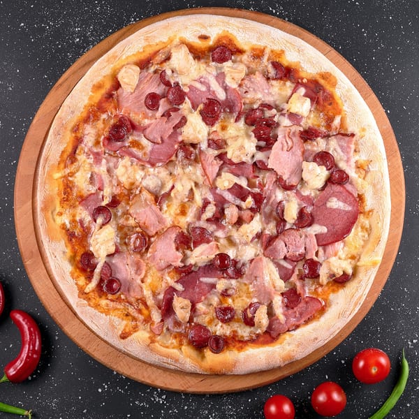 SUPPA'S PIZZA & SUBS meat lover's pizza with pepperoni, ham, and chicken on a wooden board.